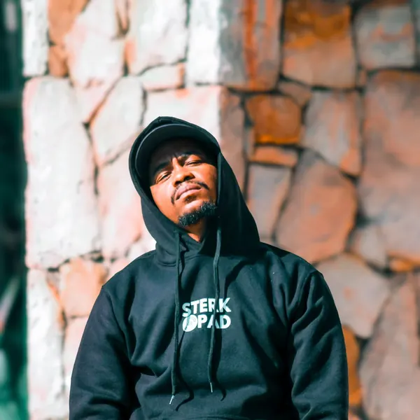 SterkOpad artist in a branded hoodie against a stone wall