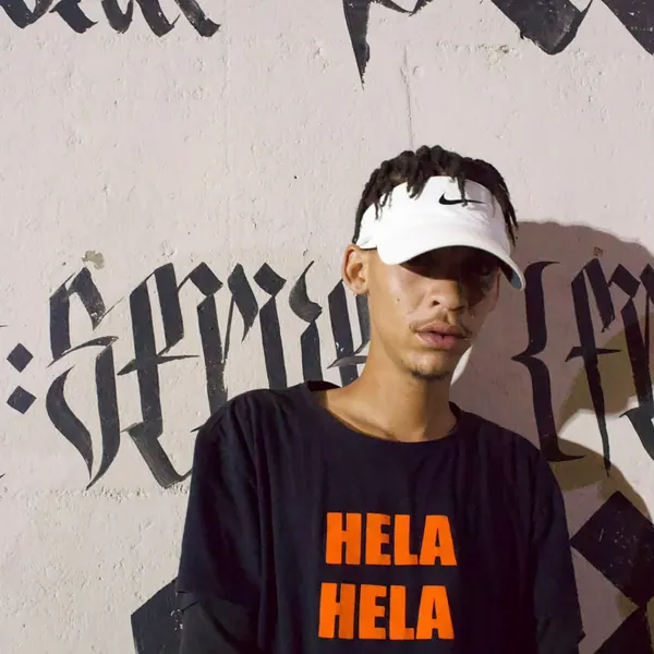 SterkOpad artist in a Hela Hela tee against a painted wall