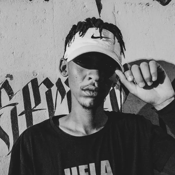 Larnie OGee against a graffiti wall in a HELA HELA tee